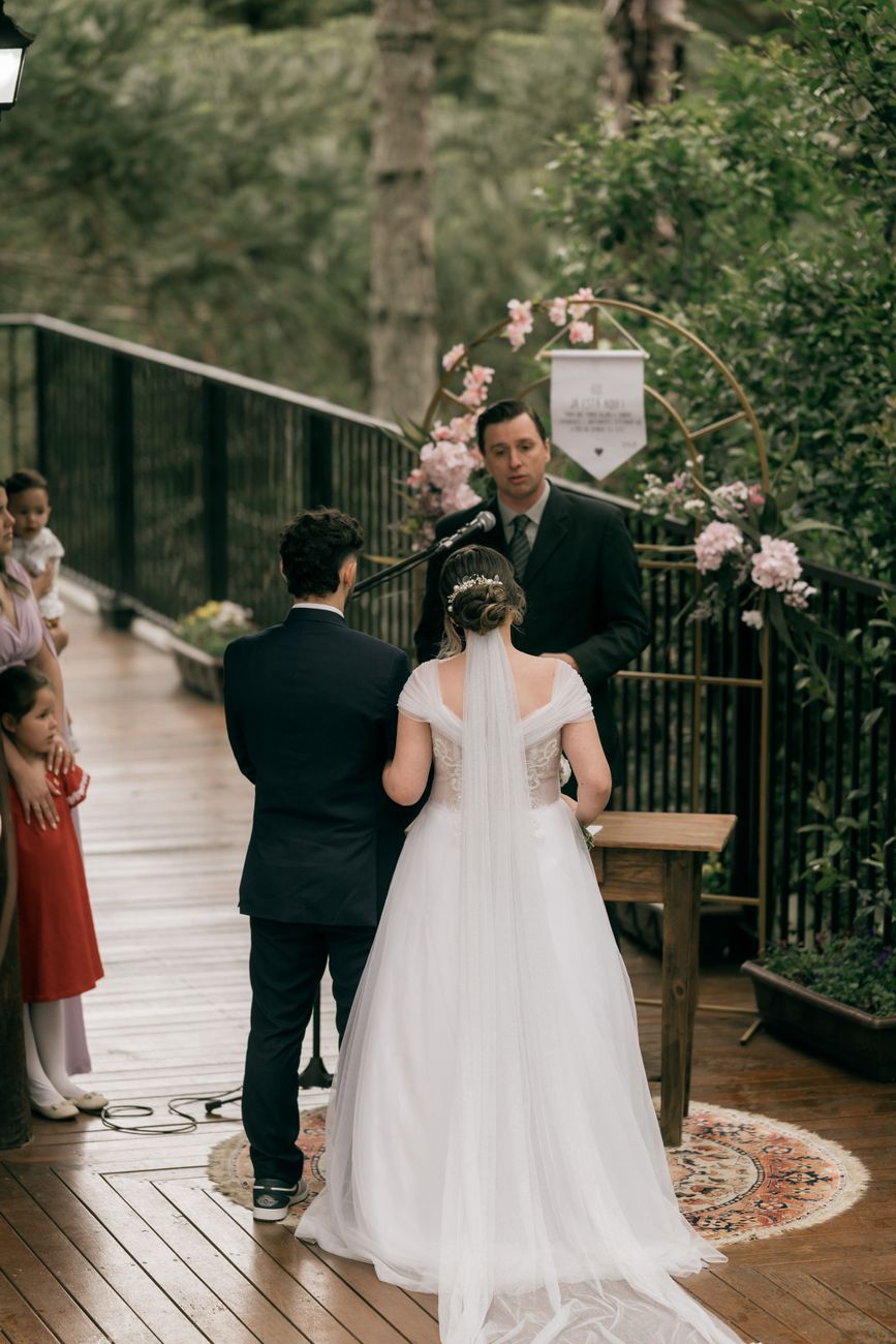 A couple at an outdoor ceremony beneath a floral arch