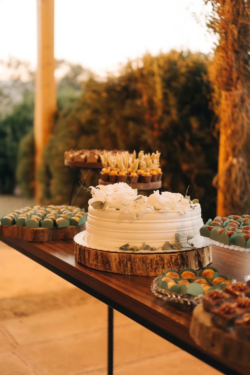 A tiered wedding cake on a dressed dessert table