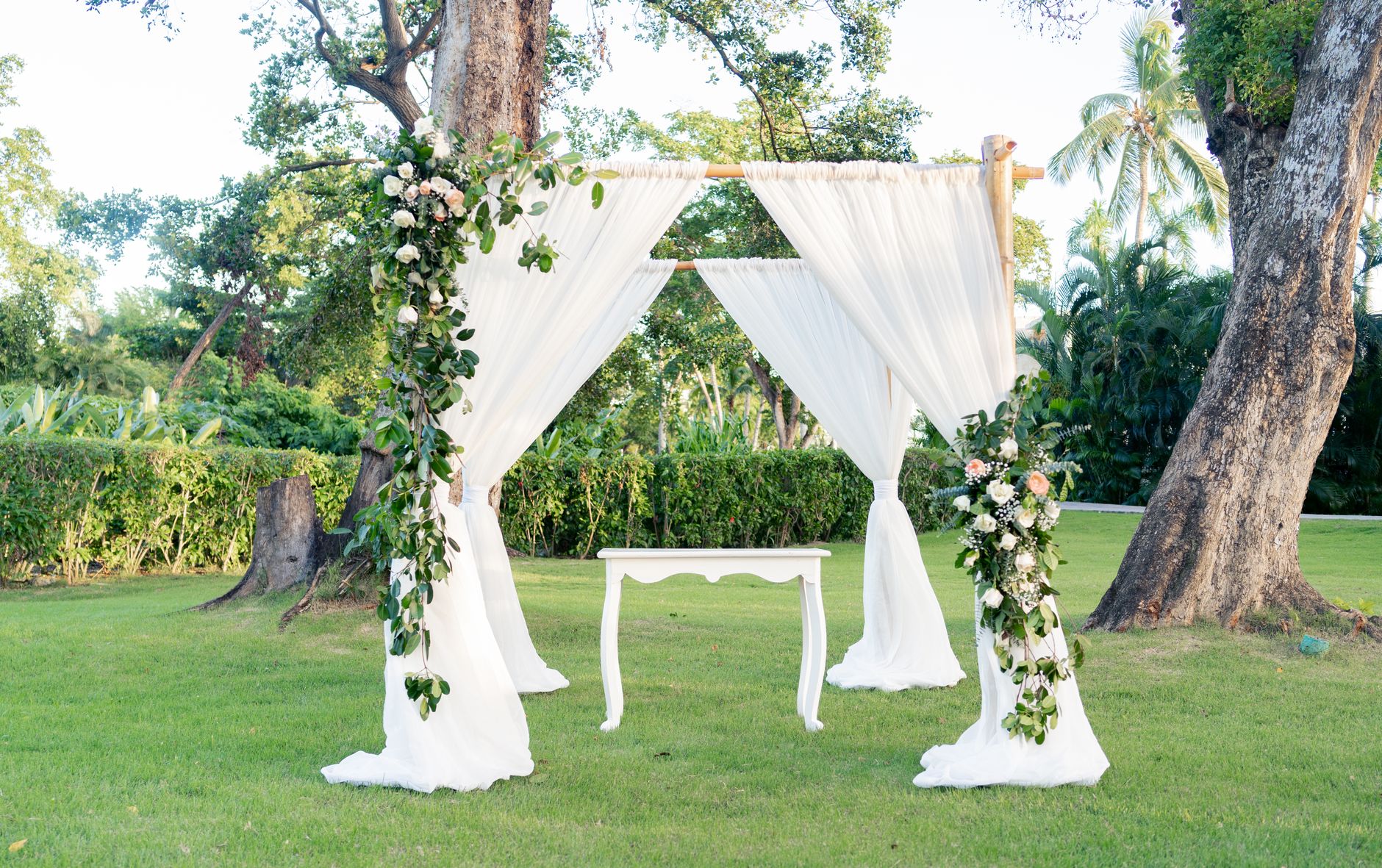 A hand-built ceremony arch dressed in white florals